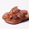 Pair of brown leather sandals with intricate designs on a white background