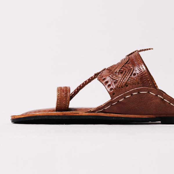 Brown sandal with detailed design on a white background