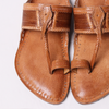 Pair of brown leather sandals with intricate designs on a light gray background