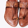 Pair of brown sandals with detailed straps on a white background