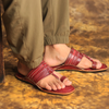 Red sandals worn with green pants on a textured surface