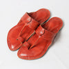 Pair of red leather sandals on a light gray background