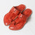 Pair of red leather sandals on a light gray background