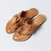 Pair of tan sandals with intricate designs on a light gray background